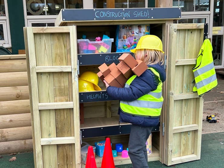 An acorn store being used as a construction play storage shed with a child collection bricks from the unit.