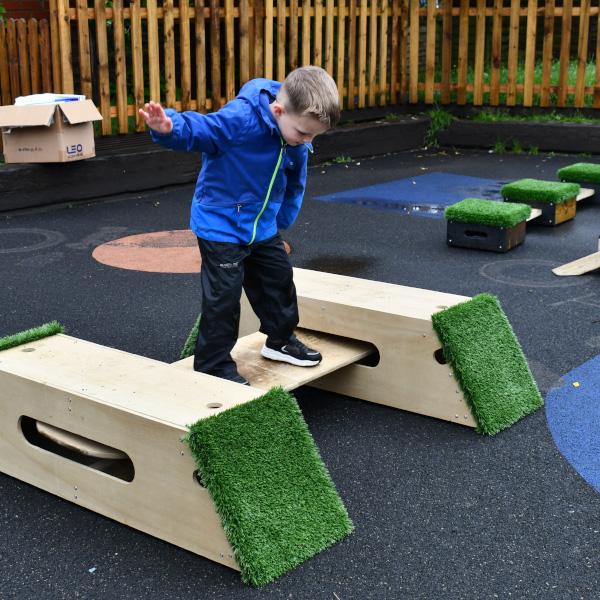 child balancing on The Rockies product in nursery playground on a wet day