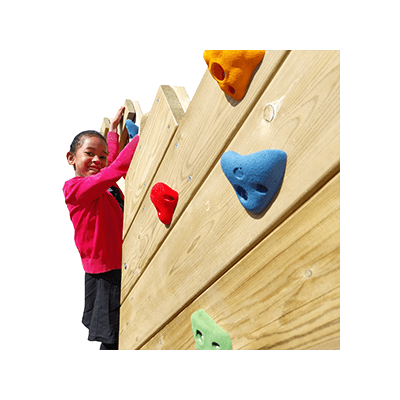 girl smiling at camera whilst climbing up a climbing wall in a playground