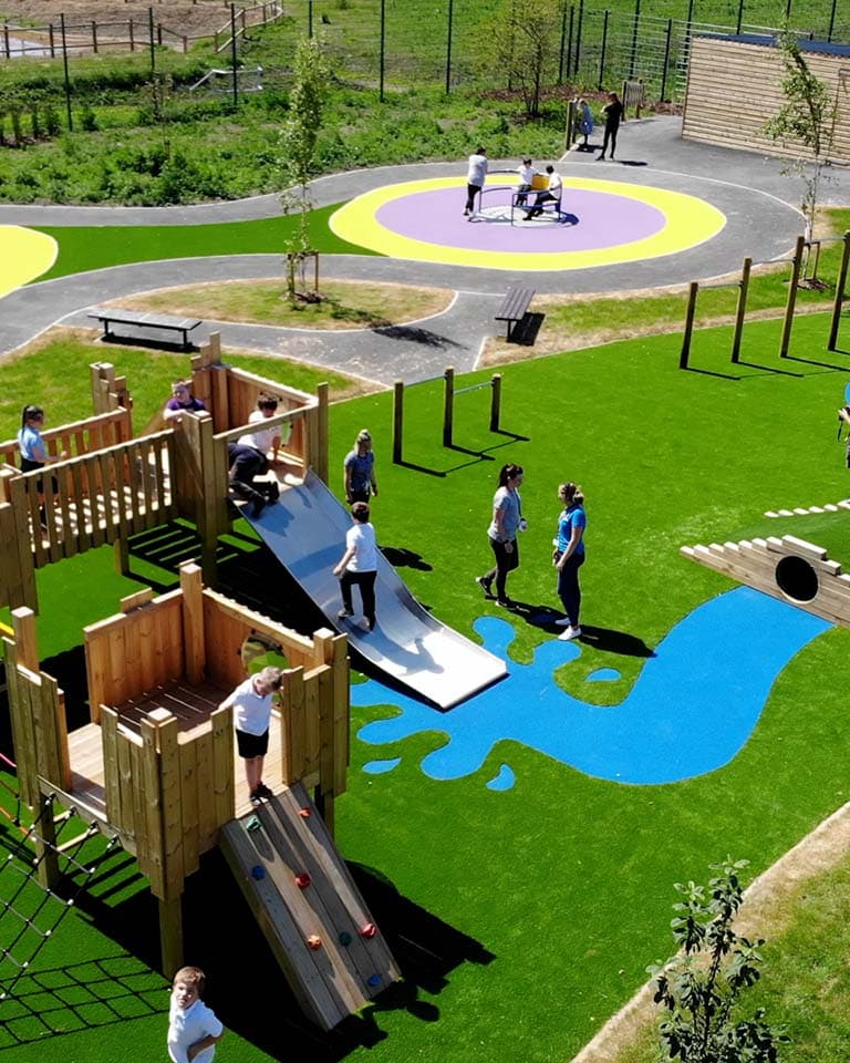 School children playing on climbing frame with slide in school playground