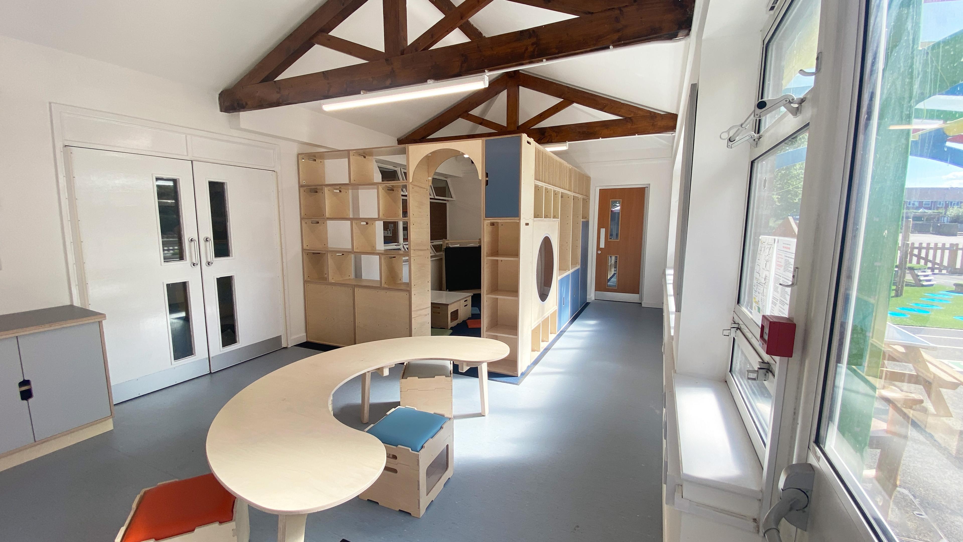 refurbished classroom with stack and sit stools, rounded tables and large storage units