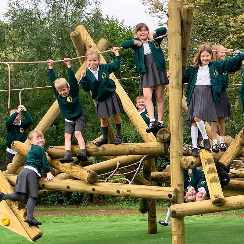 older primary school children smiling at the camera on a climbing frame