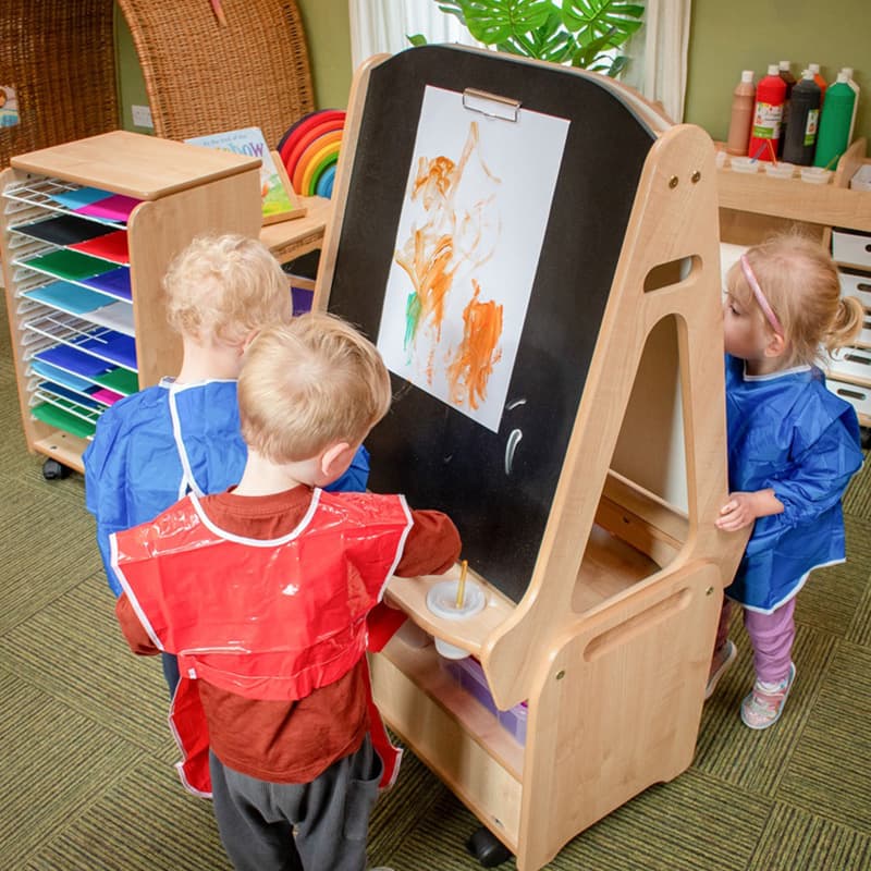 nursery children painting with the Millhouse art easel in a nursery classroom