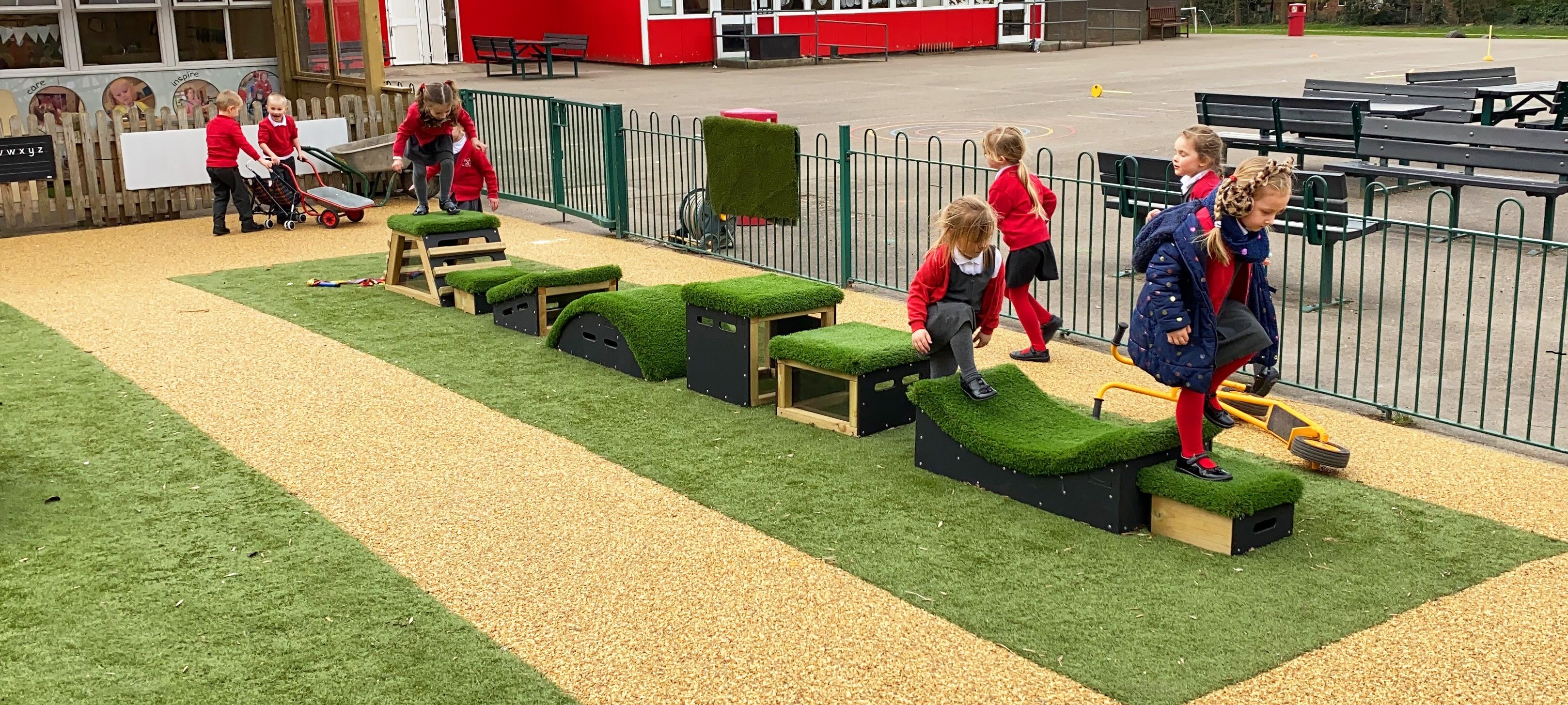 primary school children playing on Get Set, Go! Blocks in the school playground on some grass