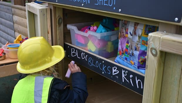 A nursery child labelling the Acorn Store chalkboard panel