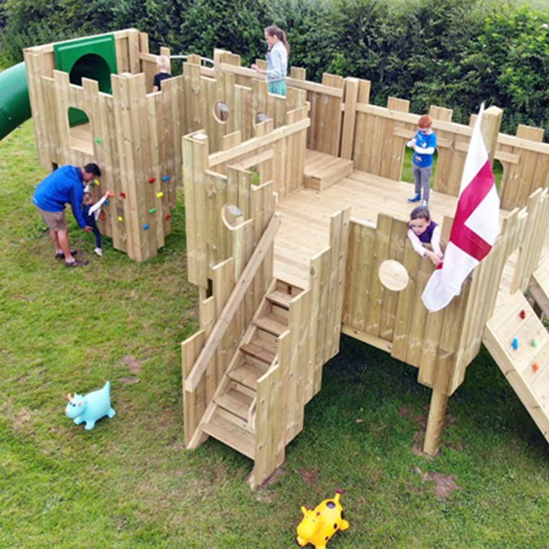 children having fun on a large wooden play tower in outdoor play area