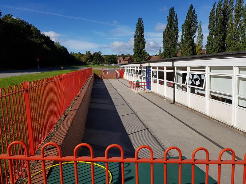 primary school with tarmac playground area and red fencing