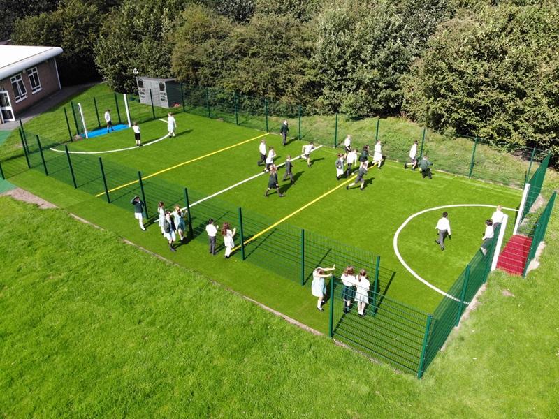 school students playing in MUGA pitch with artificial grass and fencing
