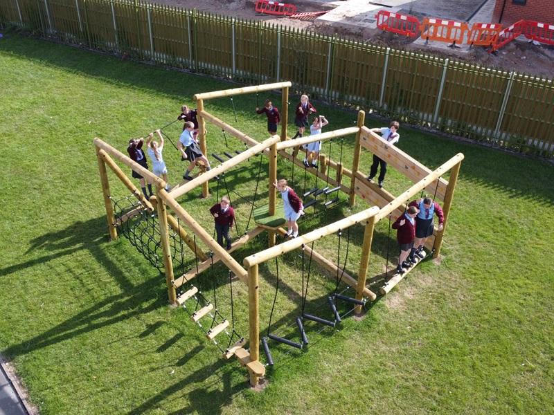 students playing on new trim trail equipment in school field