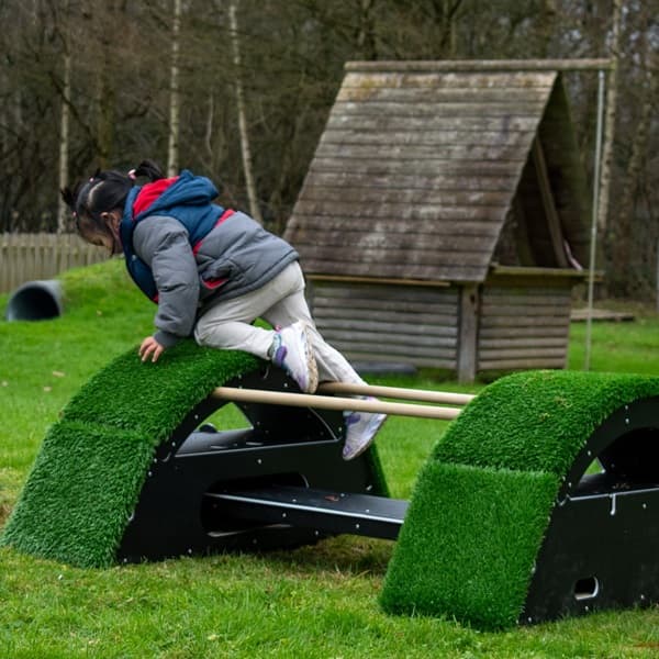 nusery child climbing on the end of The Rockies artificial grass covered block