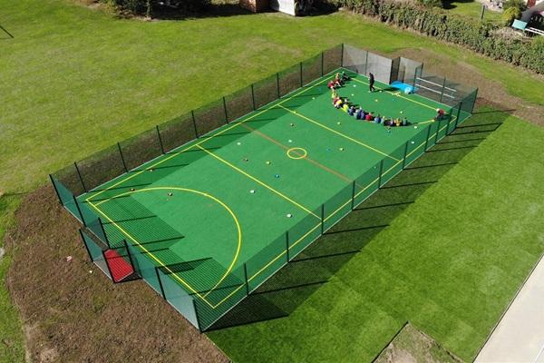 Aerial view of Woodmancote Primary’s new multi-use games area, featuring an all-weather pitch with markings for various sports, promoting active play and physical education.