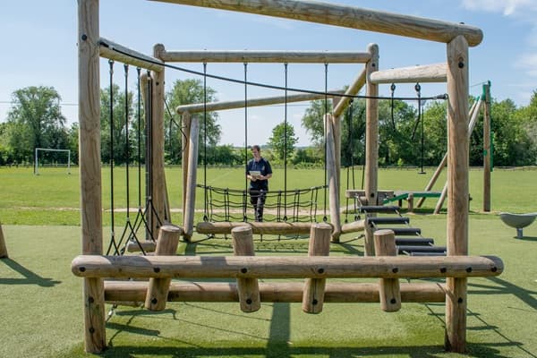 A playground inspector is checking the height of a swing set from the ground to the seat