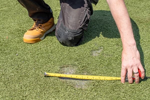 A playground inspector is sanding down a wooden playframe to ensure that there are no splinters
