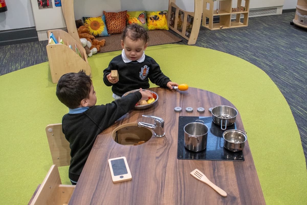 A group of three teachers are sat at a bench and are discussing the school-based nursery scheme with each other.